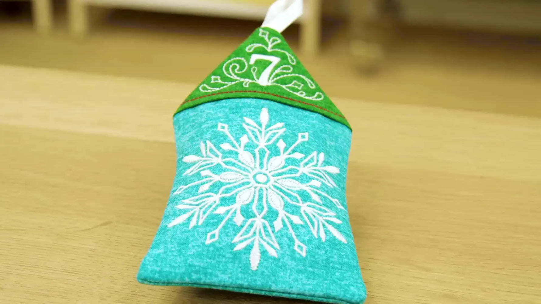 The finished Day 7 snowflake house ornament stands upright, showing crisp edges and a clean ITH finish.