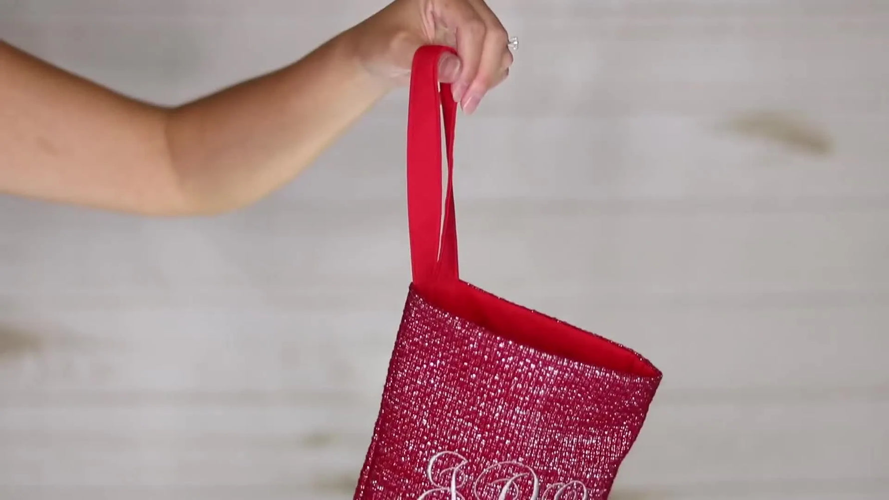 A finished sparkly red Christmas stocking with a white monogram hangs neatly, showing the clean cuff and professional shape.