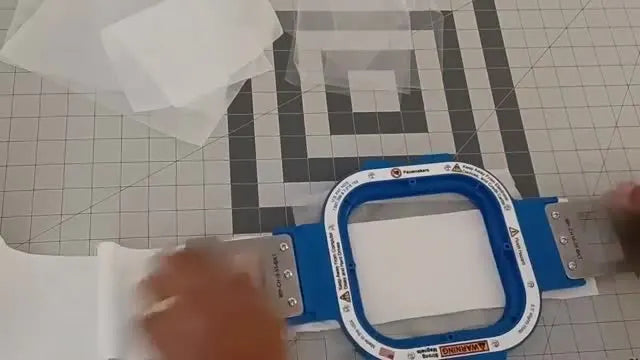 An overhead shot captures the exact moment the magnetic top frame snaps onto the bottom frame over the folded toilet paper and stabilizer stack.