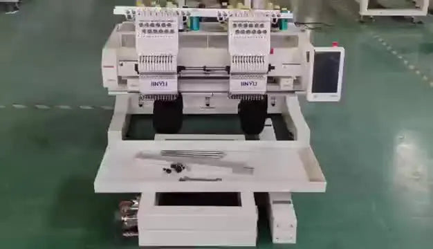 Top-down view of a two-head embroidery machine with its unassembled stand parts laid out on the floor.