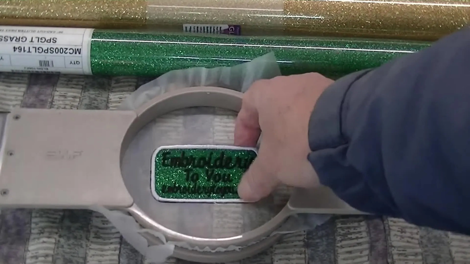 A close-up shows the finished glitter flake patch separating cleanly from the hooped Ultra Solvy with a gentle press.