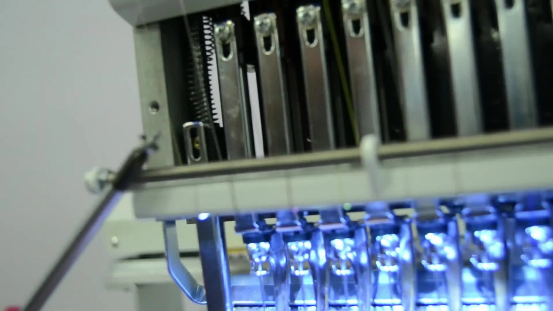 A close-up of a technician tightening the upper set screw to lock in presser foot height on a Happy Japan multi-needle head.