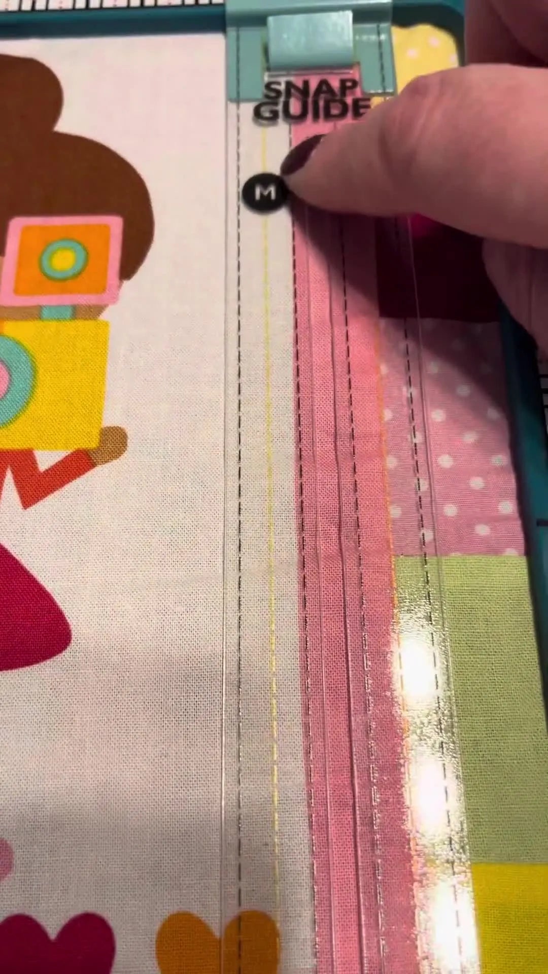An overhead view of a vertical Snap Guide ruler laid over fabric in a magnetic hoop, showing perfectly parallel alignment for straight stitching.