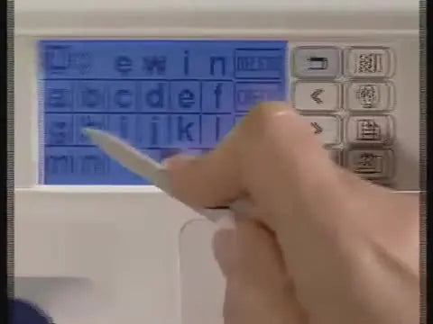 The Brother embroidery machine LCD shows the completed word “Sewing” in the built-in lettering screen.