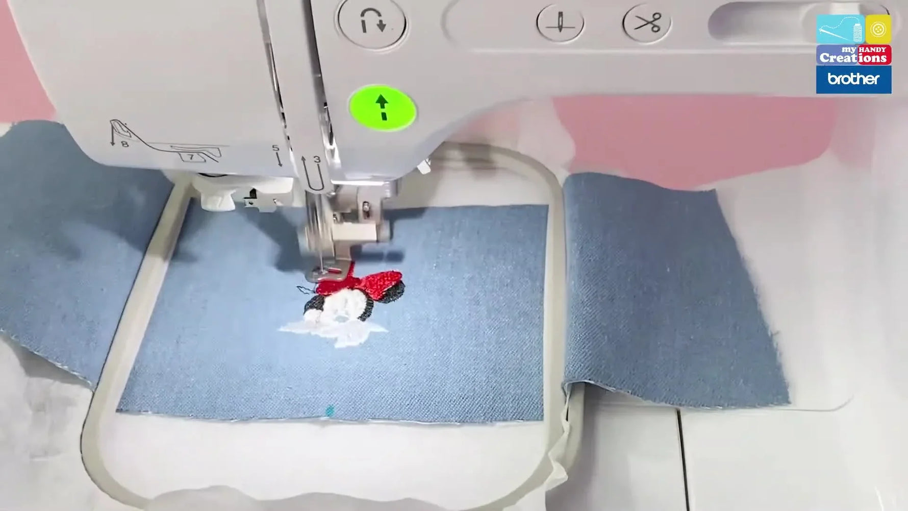 A close-up of the Brother NV180D stitching a Minnie Mouse design onto blue denim inside a 10x10cm hoop.