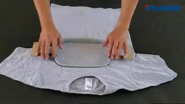 A close-up shows the rectangular magnetic hoop snapping shut on a grey cotton T-shirt, clamping the fabric flat and ready for production.