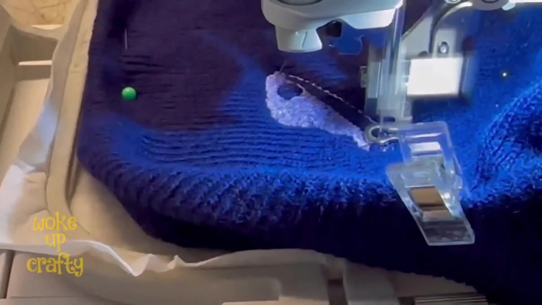 A close-up of the Brother SE630 stitching a butterfly wing through a clear wash-away topping on a ribbed knit beanie.