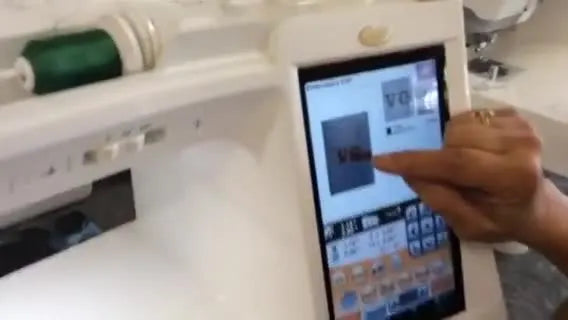 The Baby Lock screen shows the new “VG” letters precisely overlaid on the camera image of the existing “LG” embroidery for accurate placement.