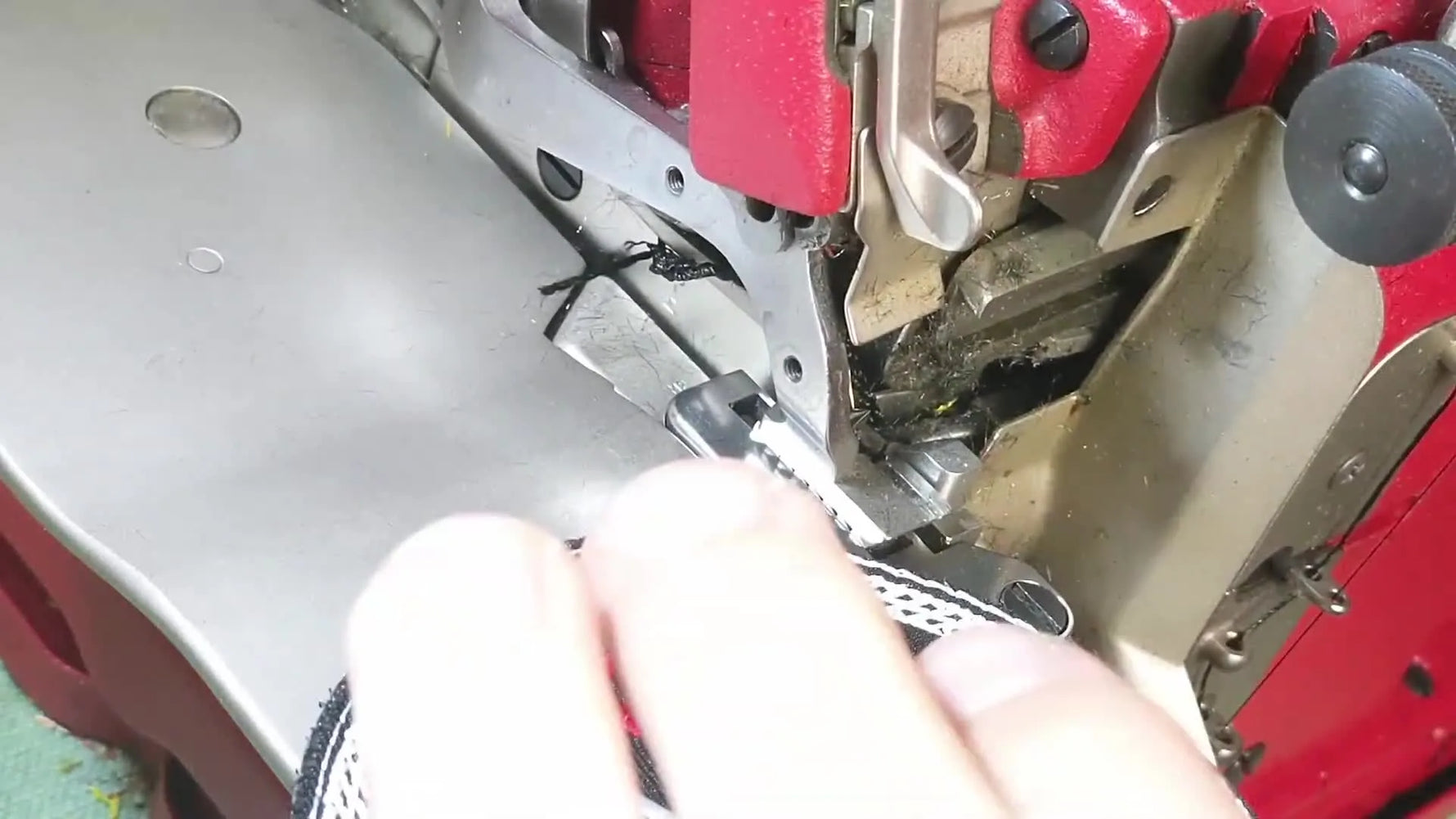 A close-up side view of a Velcro-backed patch entering the Merrow MG-3UV mechanism as the edging begins.