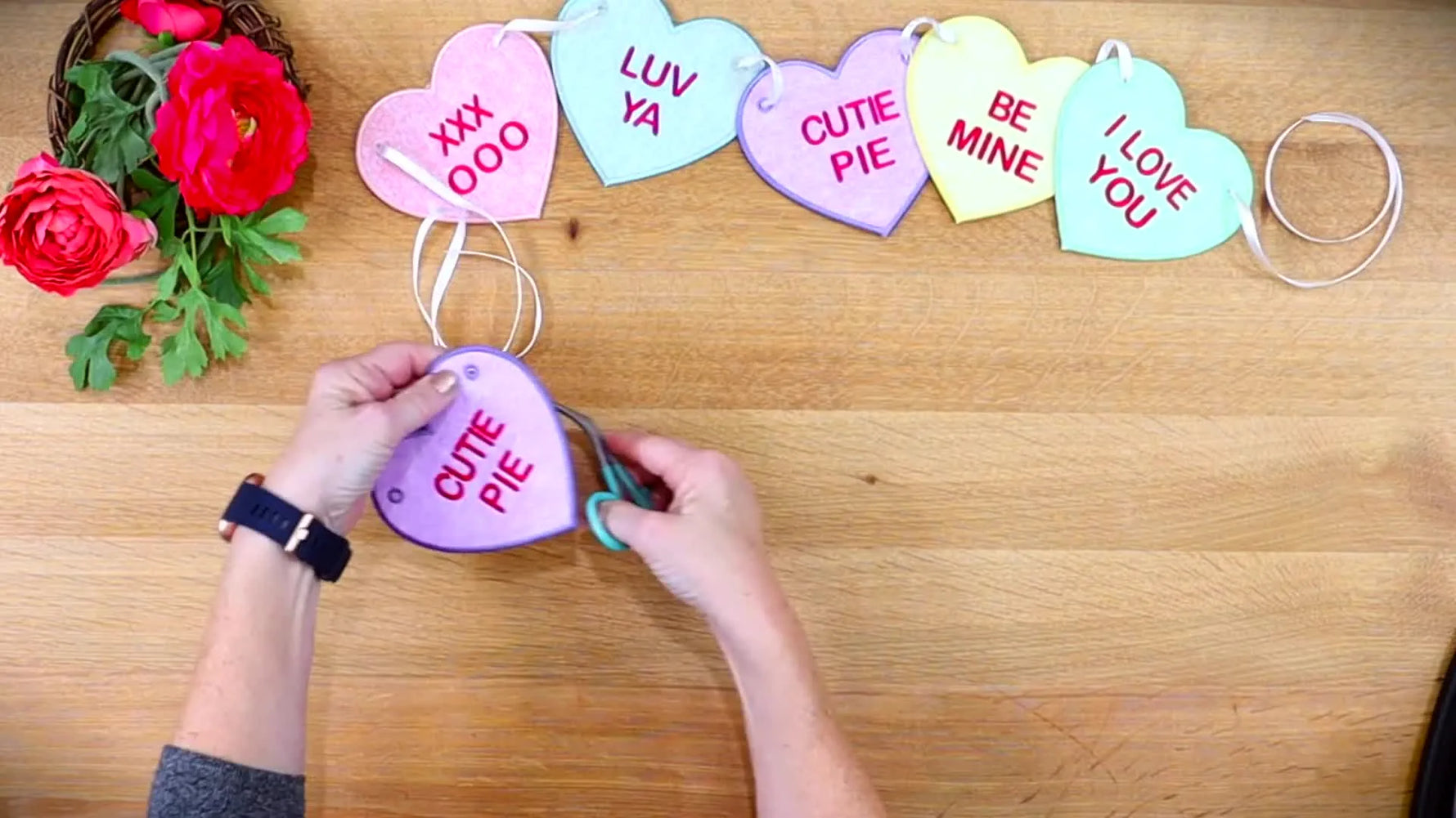 A finished string of stitched candy-heart ornaments connected with ribbon, laid out as a complete bunting.