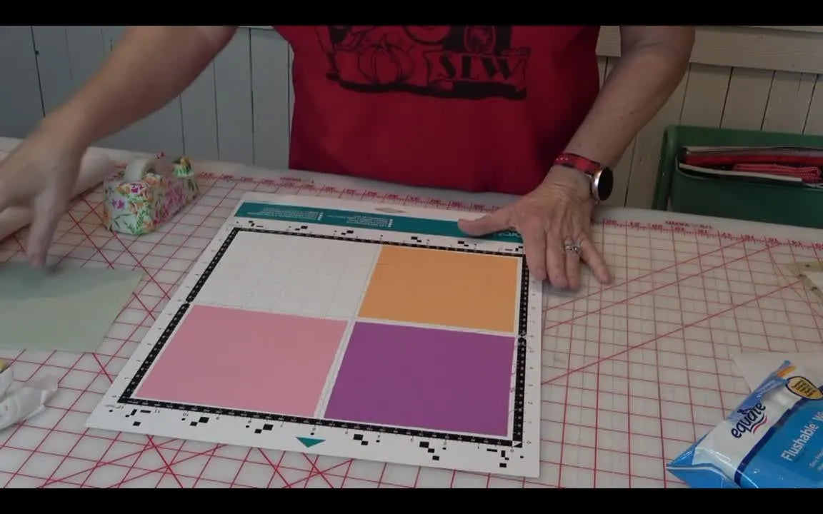 Four fused fabric squares are positioned in the quadrants of a low-tack ScanNCut mat, ready for a background scan and perfectly aligned cuts.