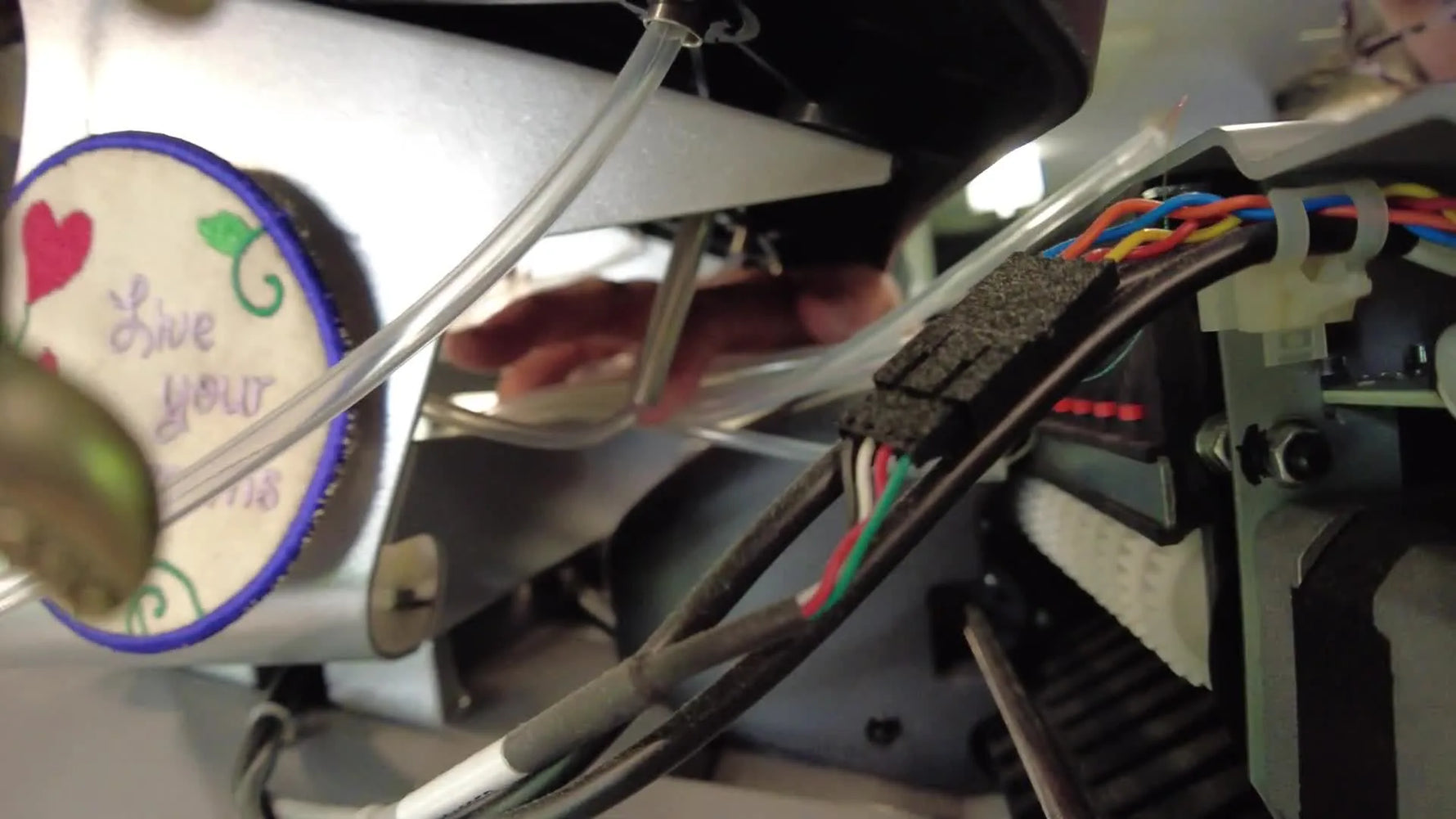 Close-up inside the Summit machine head showing clear thread feed tubes detached near internal gears and wiring.