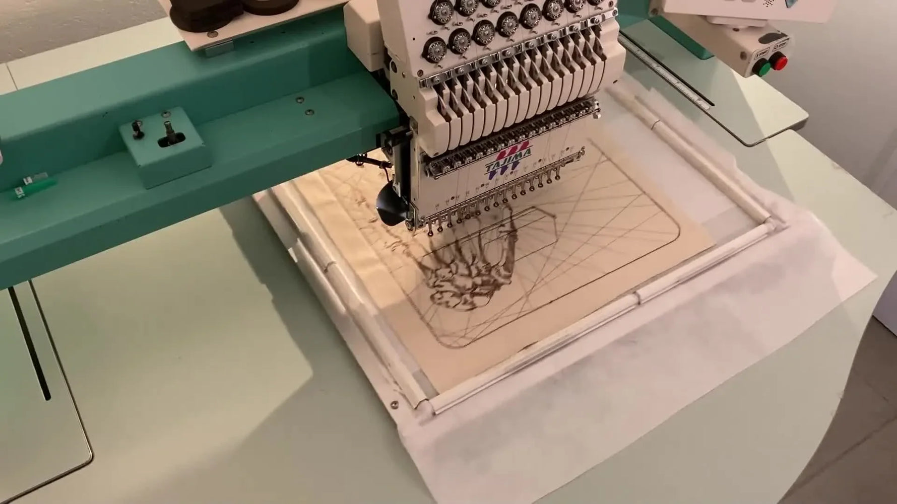 Close-up of an embroidery machine stitching a skeletal hand design onto the fabric.