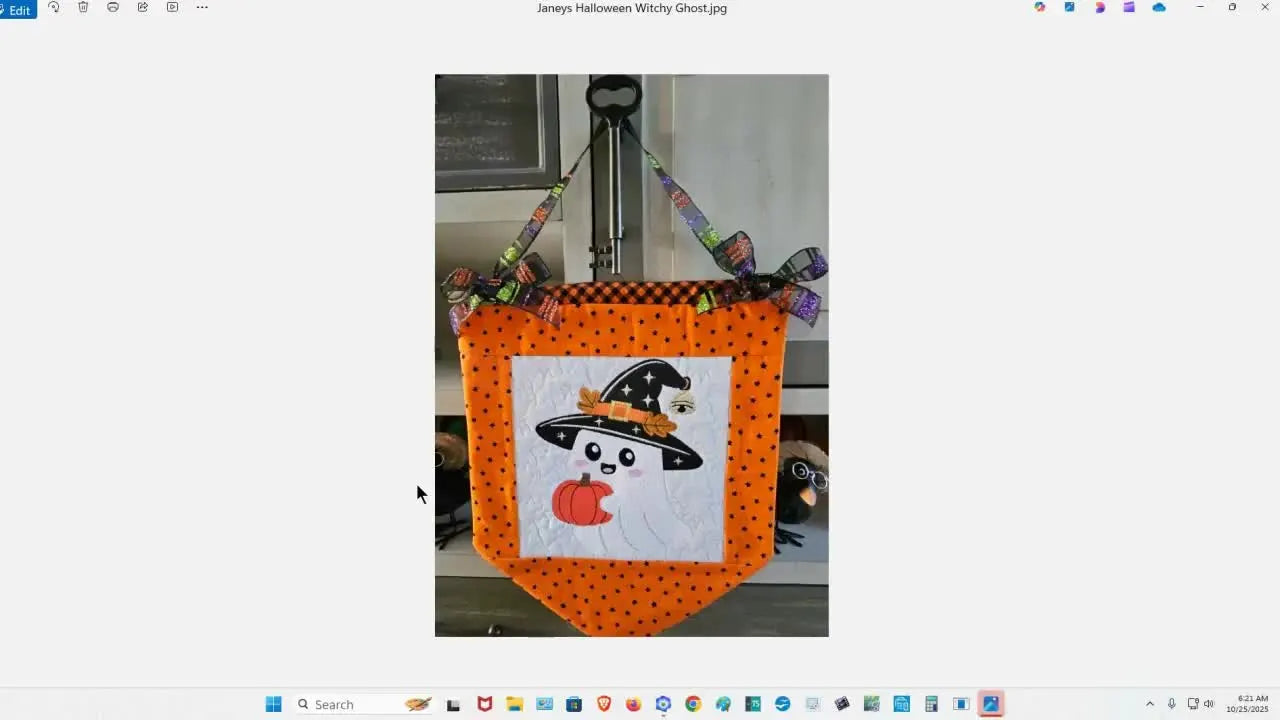 A finished orange hanging banner featuring the completed “Witchy Ghost” embroidery block as a real-world example of the design’s final look.