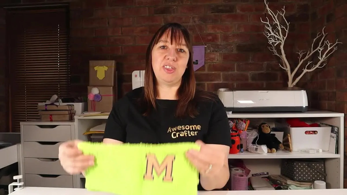 Woman holding a lime green flannel with yellow-orange applique letter M.