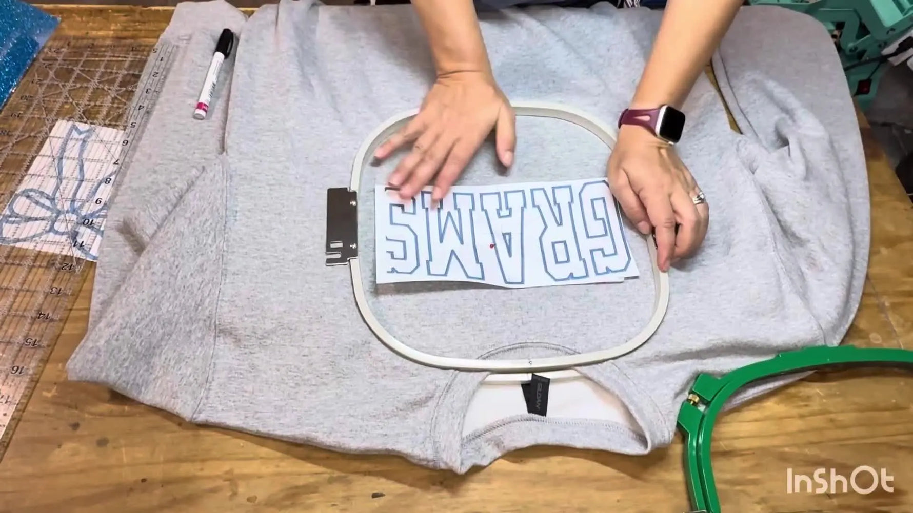 Hands press the inner hoop into the outer hoop, locking a thick sweatshirt firmly in place for applique stitching.