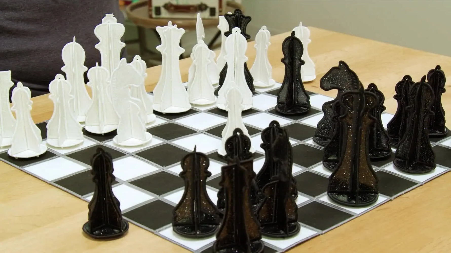 A fully assembled black-and-white freestanding embroidered chess set displayed on a chess board.