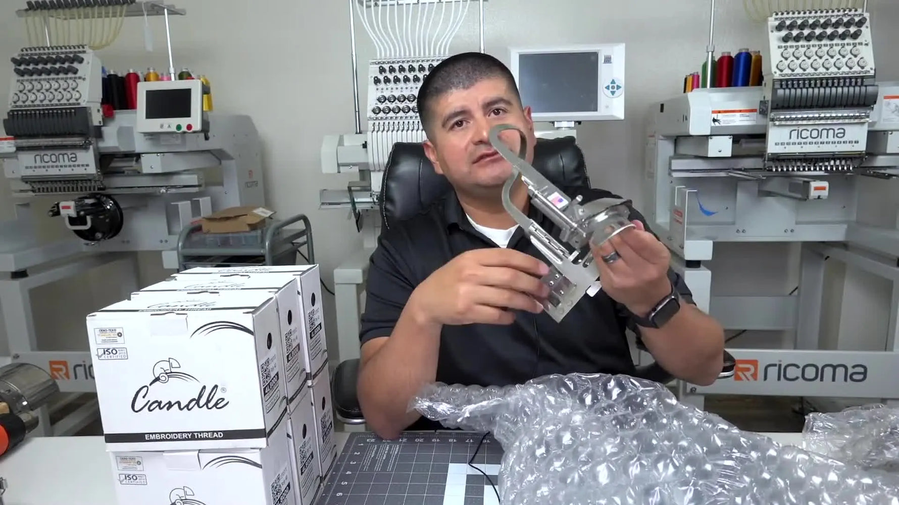 The host holds up a shiny Gen 2 cap frame just after unwrapping it, highlighting the heavy-duty build and details.