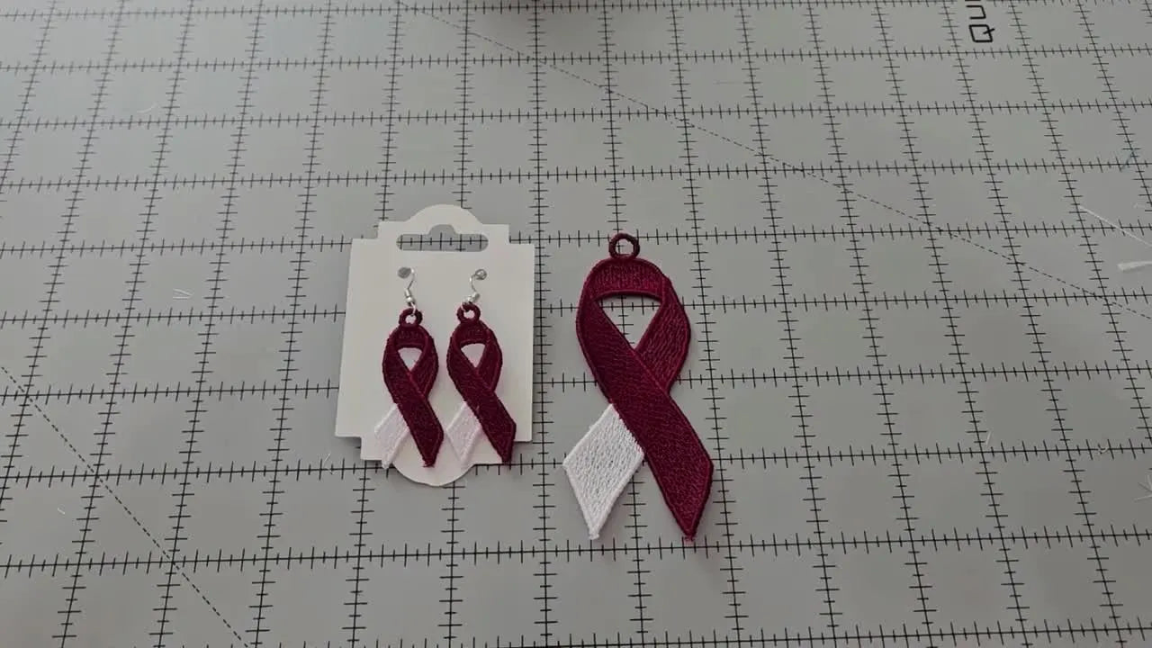 Finished maroon-and-white FSL ribbon earrings and a larger ribbon laid flat on a cutting mat after washing and drying.