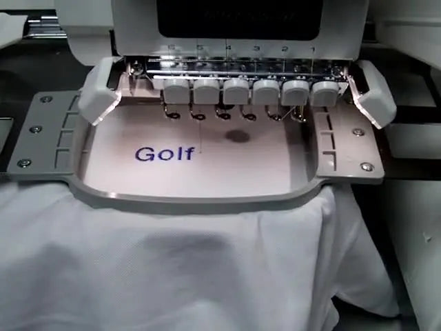 A close-up of the Brother PR 650 stitching at high speed, showing needle-bar motion blur while embroidering the hyphen in “Golf‑Pro.”
