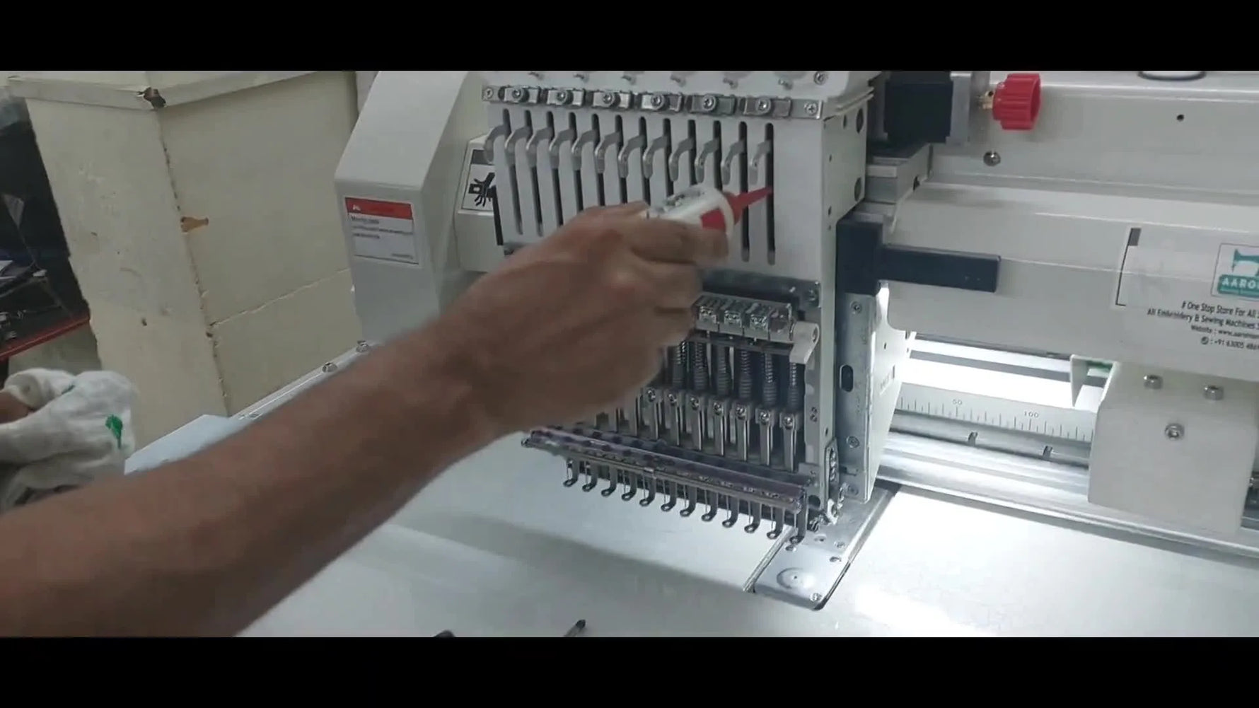 Close-up of oil being applied to the needle bar springs with the front cover removed on an HSW multi-needle embroidery machine.