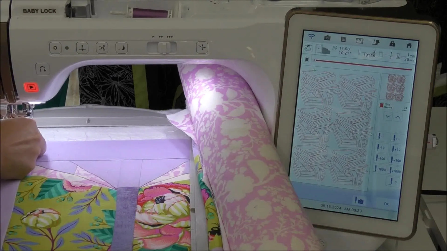 A Baby Lock Solaris stitches a book-themed quilting fill across a thick quilt sandwich while the hoop moves smoothly under the machine head.