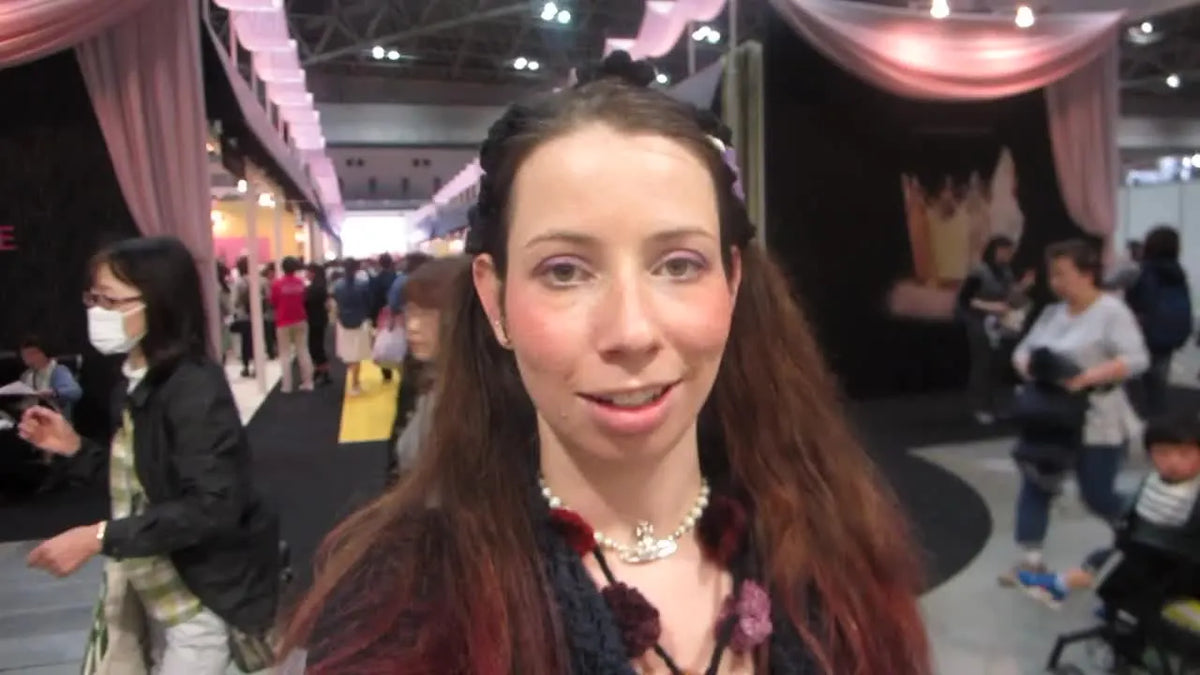 Woman in pigtails talking to the camera at a large indoor event.