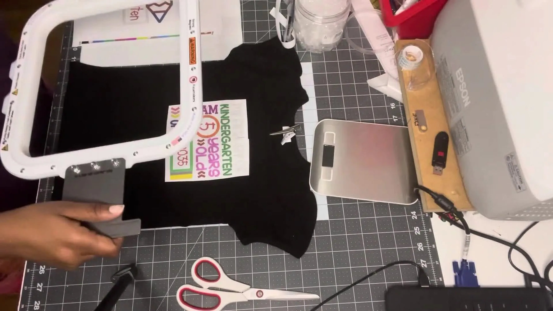 The top magnetic frame is held over a hooped toddler T-shirt right before it snaps into place for fast, even tension.