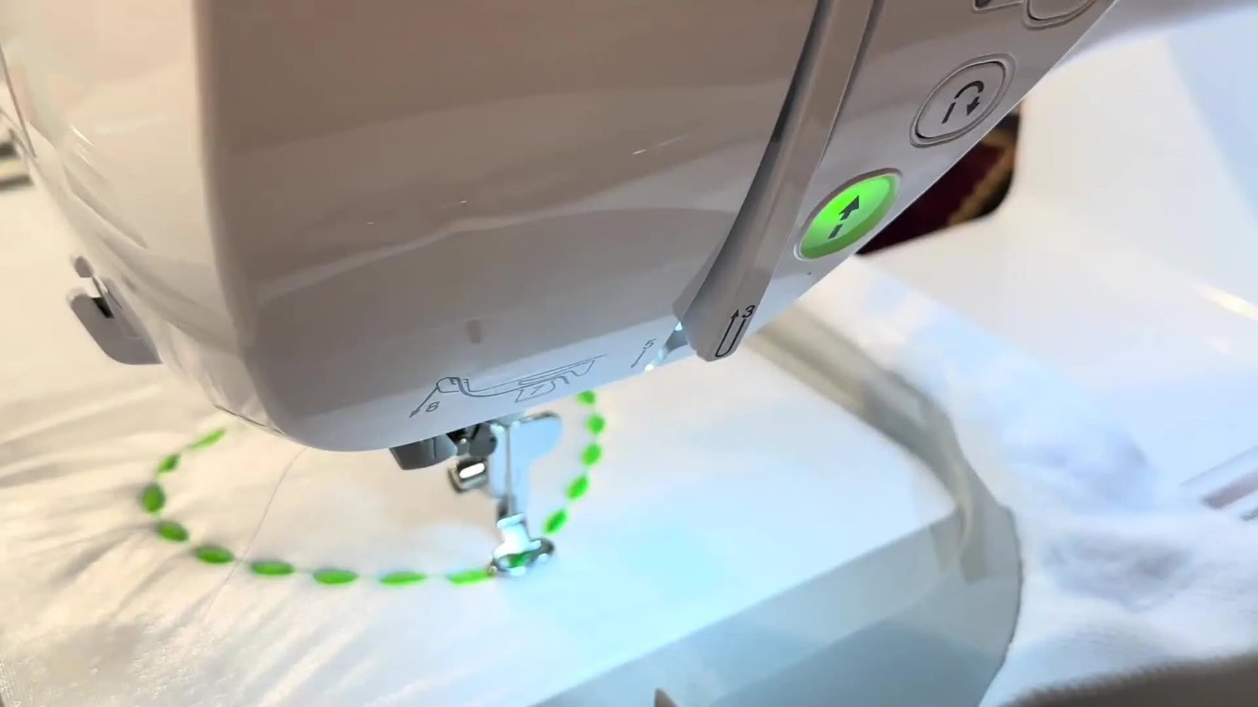 Close-up of the Brother Innov-is NQ3550W automatic needle threader mechanism descending to pull thread through the needle eye.