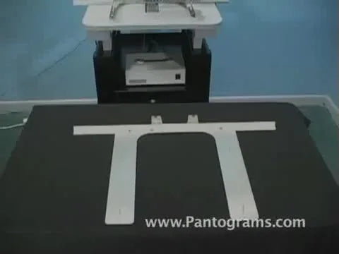 Hands press the Carpet Master frame onto a floor mat so the spikes bite cleanly and hold the embroidery area flat.