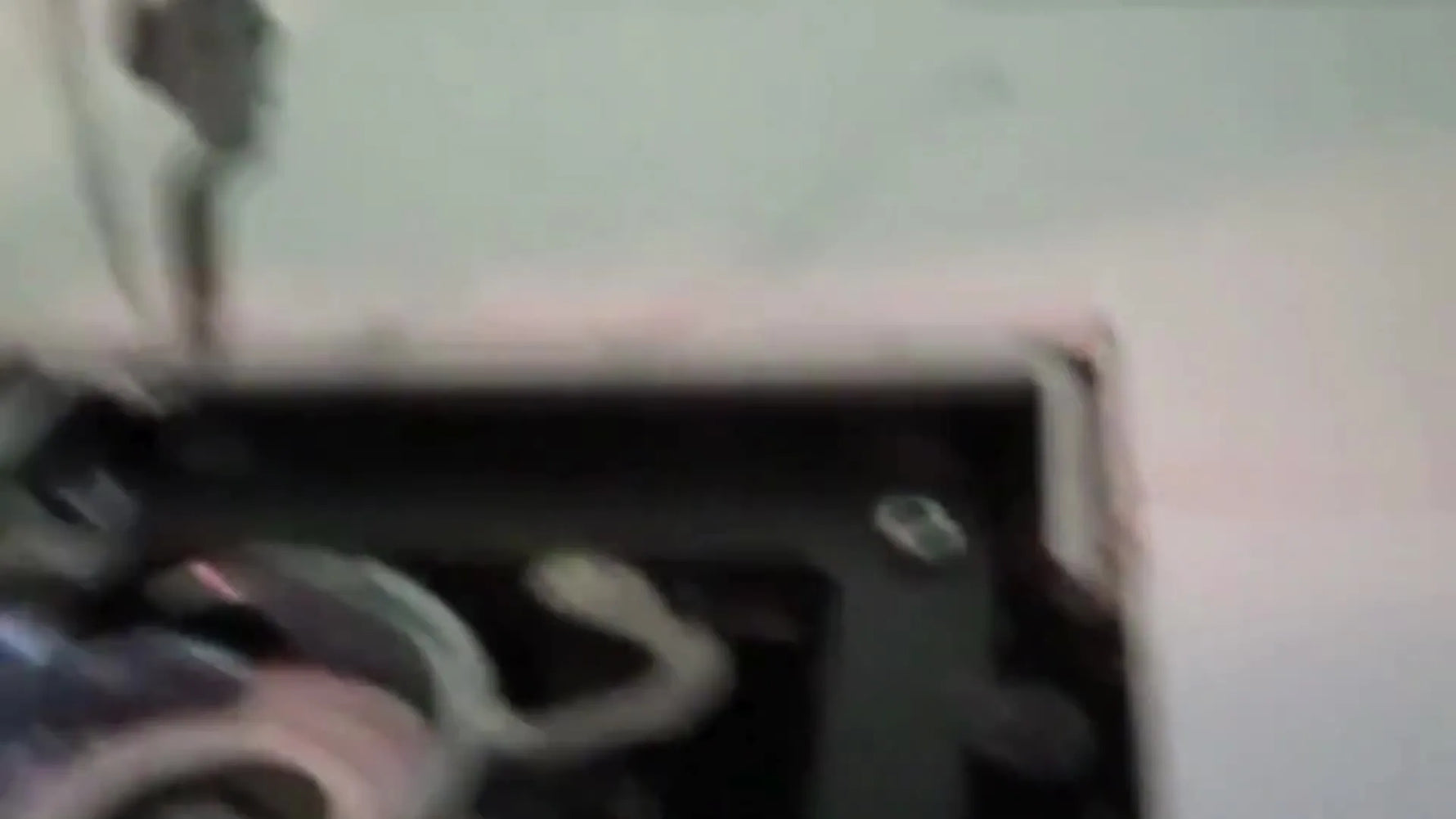 A close-up shows a small brush sweeping lint from the Janome hook race area under the needle plate.
