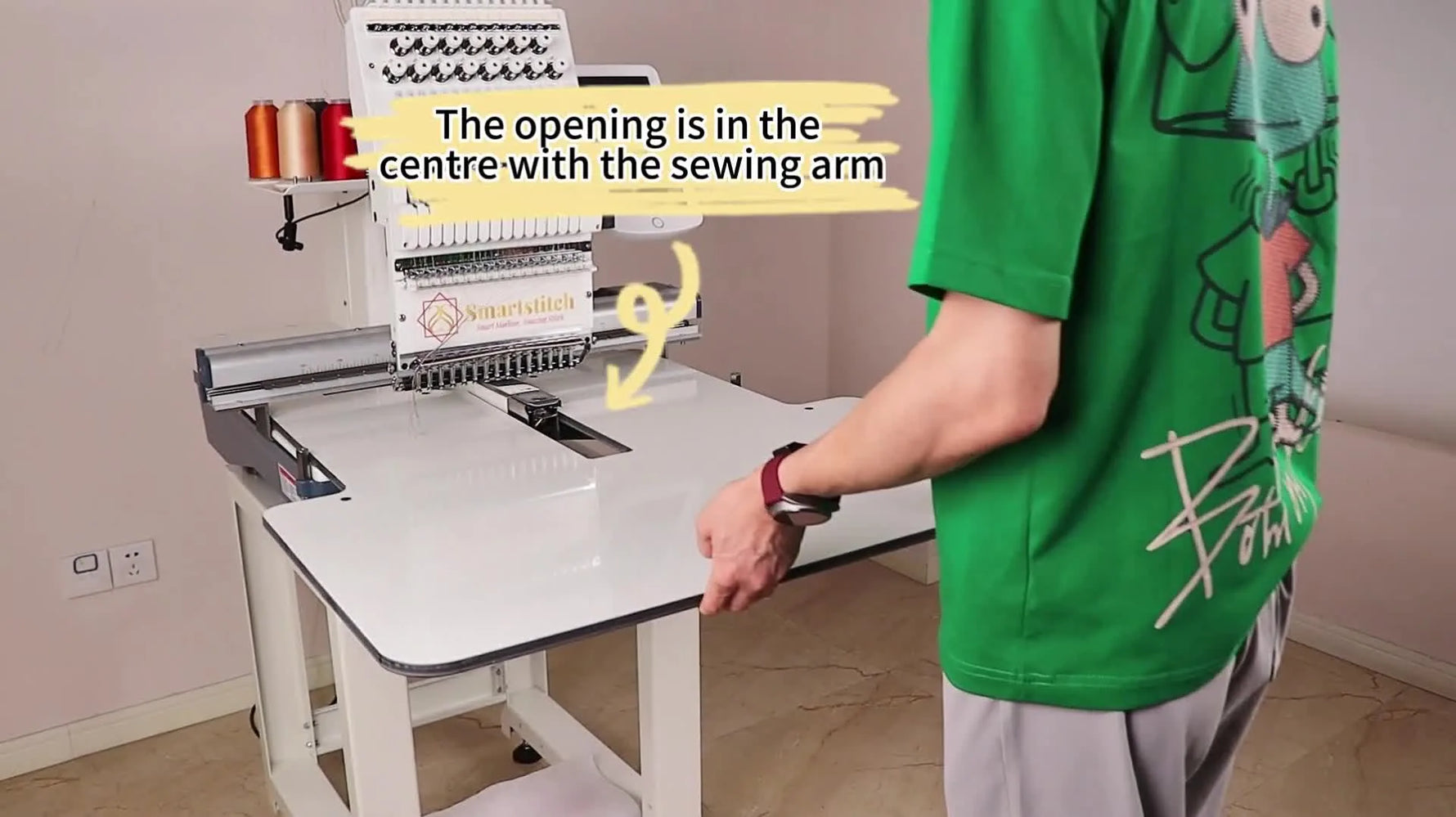 An operator slides the large extension table onto the Smartstitch machine arm to prepare for large-format embroidery.