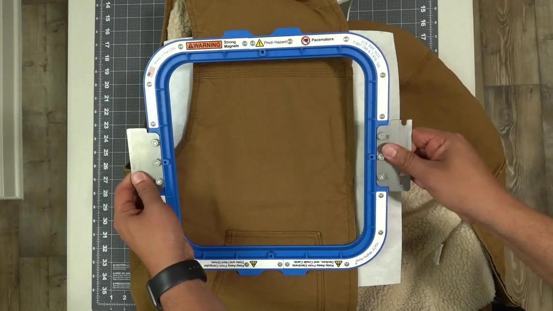 A 10x10 magnetic hoop is lowered onto a very thick winter vest on a hooping station, moments before it snaps into place.