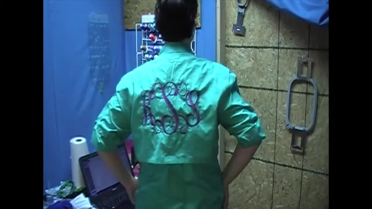 The finished Magellan fisherman shirt is shown worn from the back, highlighting a large monogram placed cleanly under the vent flap with minimal puckering.