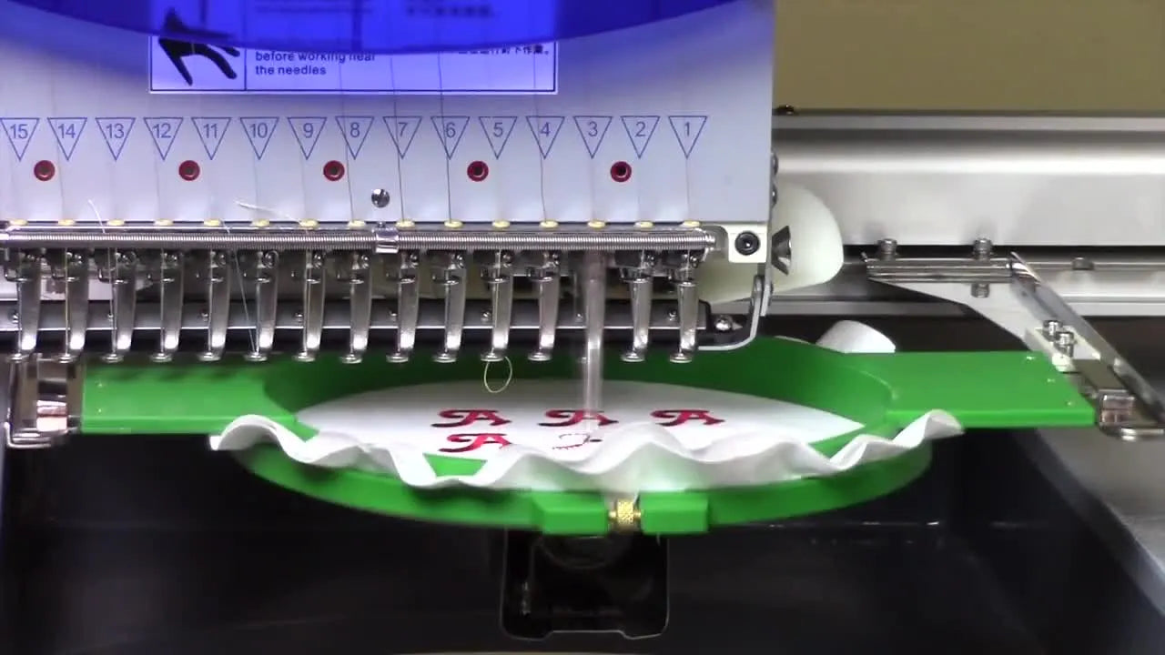 A close-up of the Avancé machine actively stitching a 3×3 grid of red logos inside a round hoop.