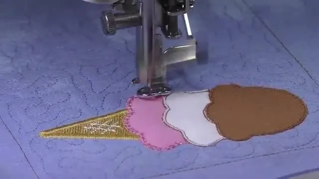 A close-up of the embroidery machine stitching satin borders around the colorful ice cream scoops inside the hoop.
