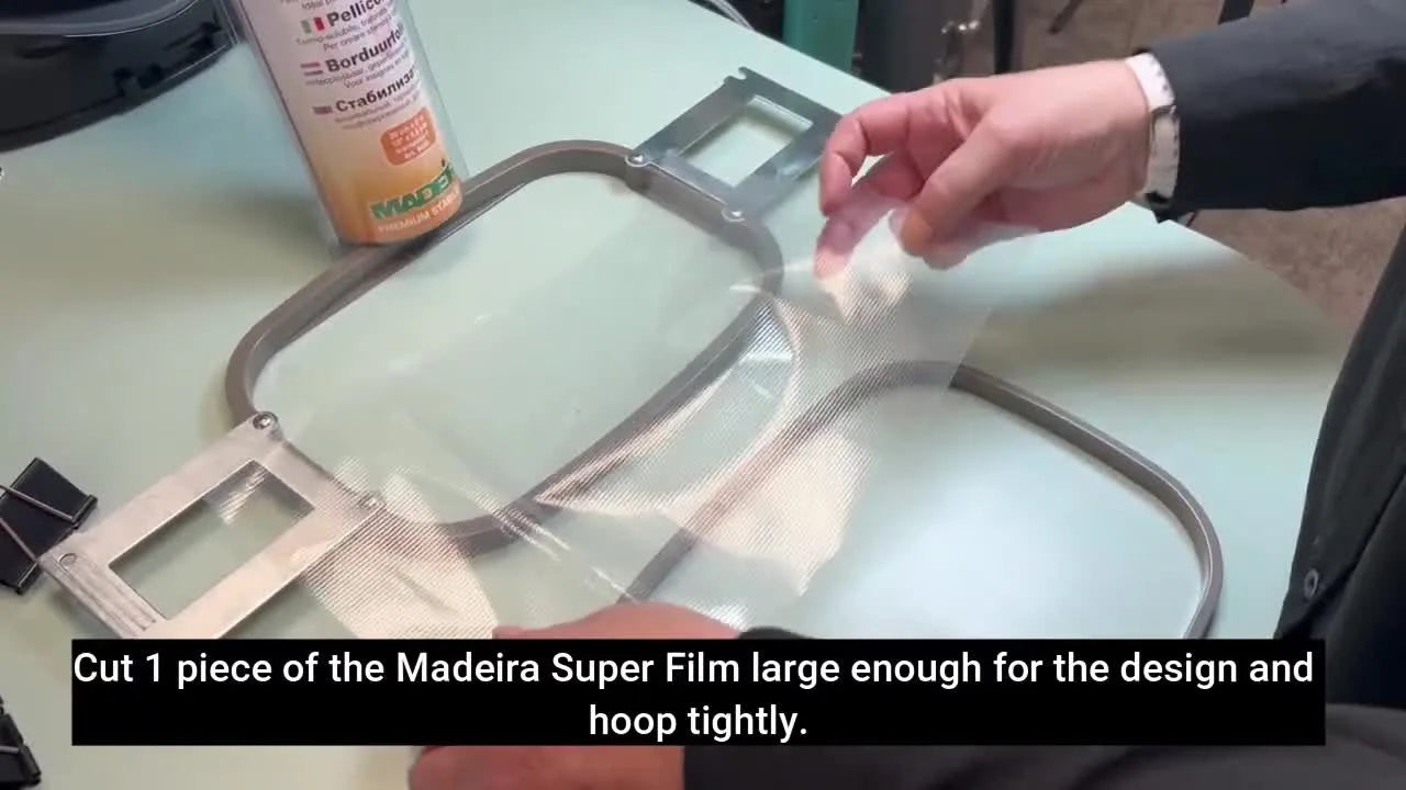 A standard tubular embroidery hoop clamped shut with four large binder clips to hold thick Madeira Super Film securely for an ITH coaster run.