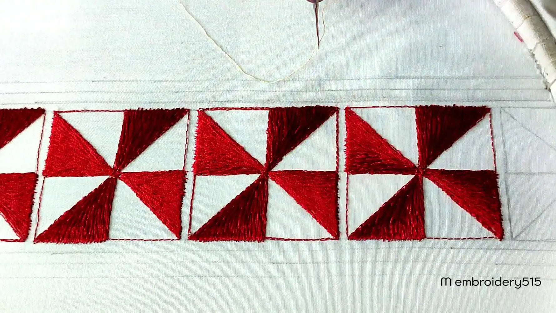 Embroidery machine starting to fill an empty triangle with gold thread next to a red-filled segment.