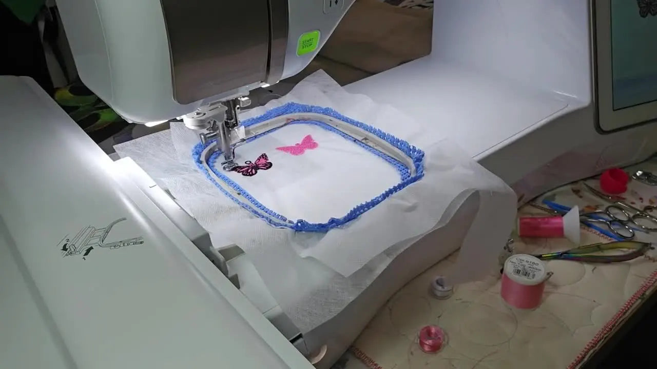 A close-up reveal of the finished FSL butterfly earrings and matching butterfly gift tag still in the hoop, fully stitched and ready to rinse away the stabilizer.