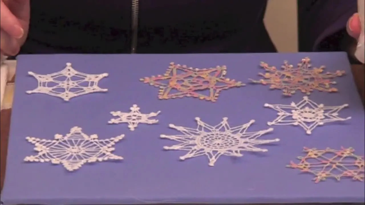A close-up shows glitter glue being dotted onto the tips of a finished free-standing lace snowflake for lightweight sparkle.