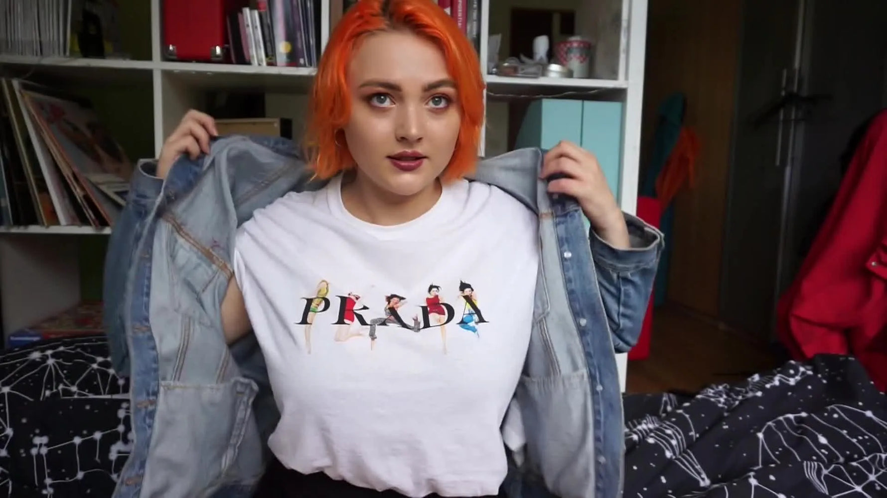 Woman in orange hair showing off her denim jacket with patches.