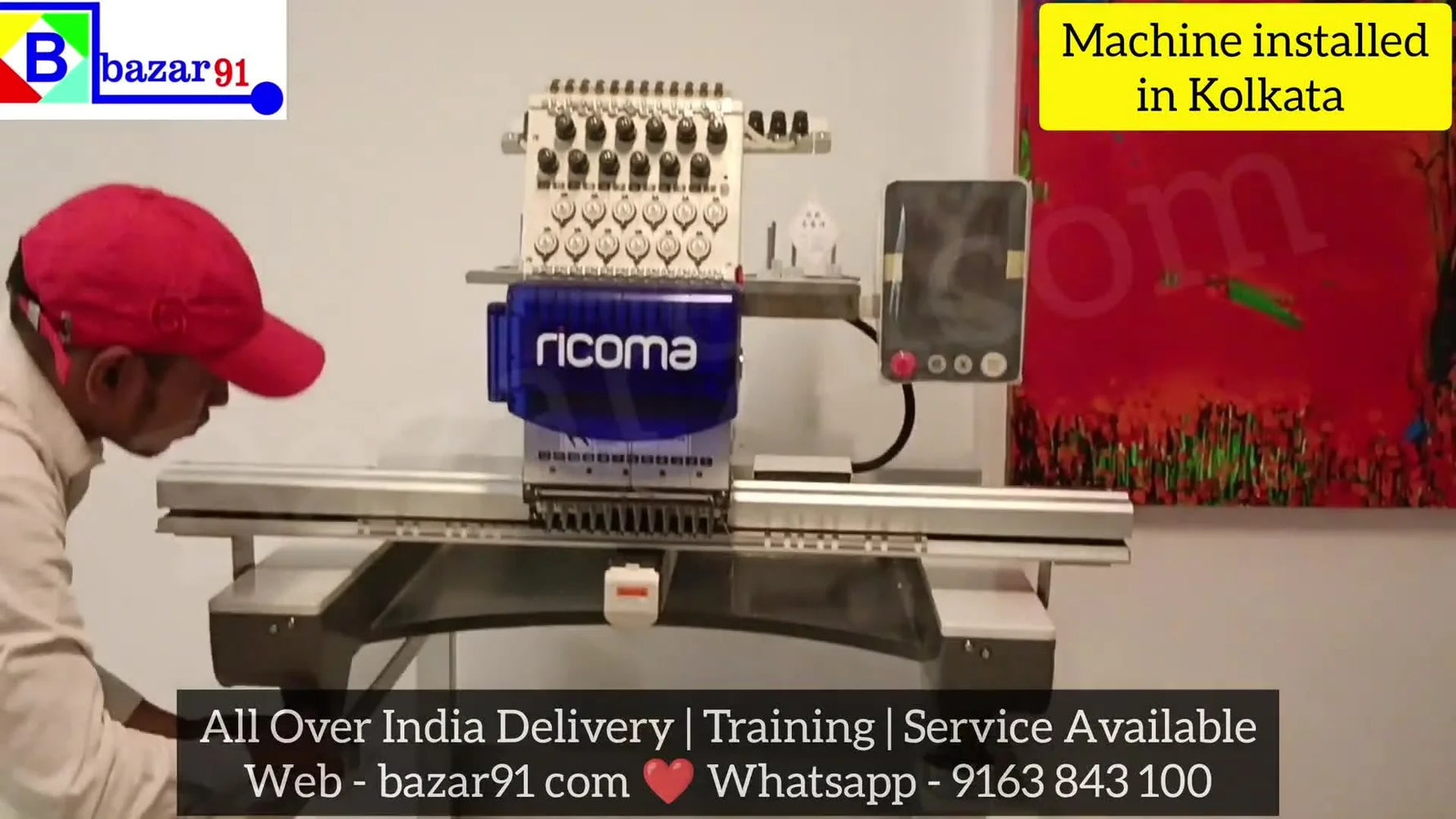 Two workers carefully lift and place the heavy embroidery machine head onto its assembled stand.