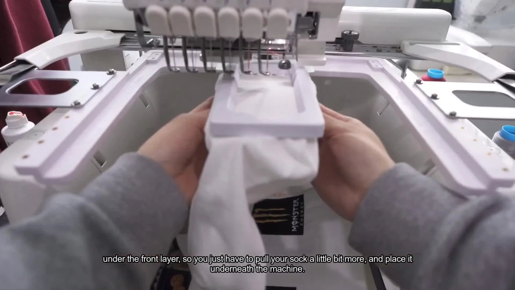 A close-up demonstration of tucking the sock under the machine arm so the back layer can’t get stitched to the front during embroidery.