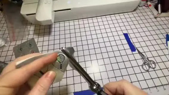 A close-up shows the correct scissor angle and smooth gliding motion used to trim vinyl earrings cleanly without jagged edges or backing showing.