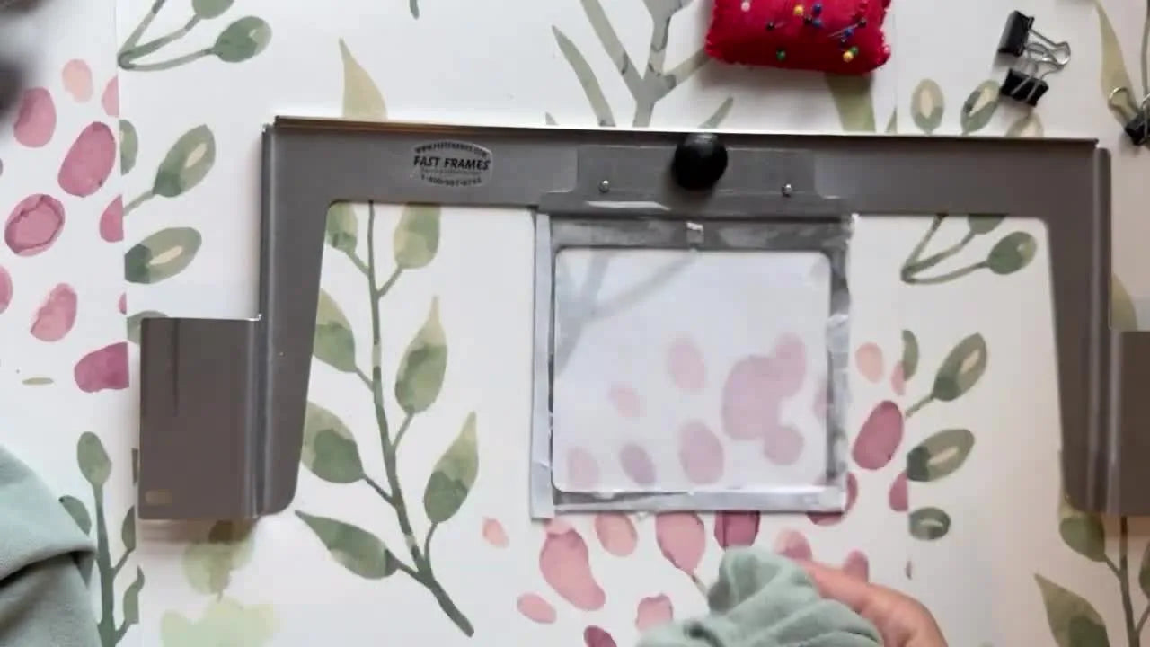 Hands hooping a sweatshirt sleeve onto a Fast Frame with sticky stabilizer.