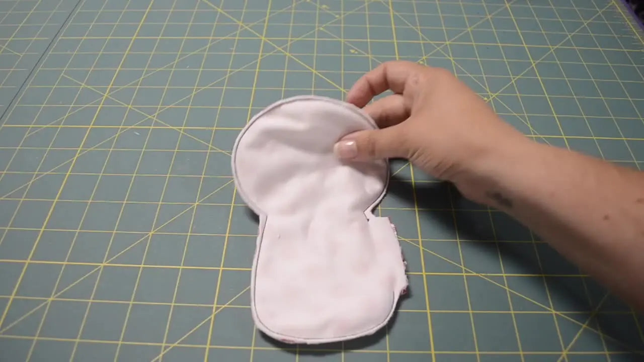 The finished Lolly Dolly stuffed toy stands upright, showing the completed face, cheeks, and heart details.