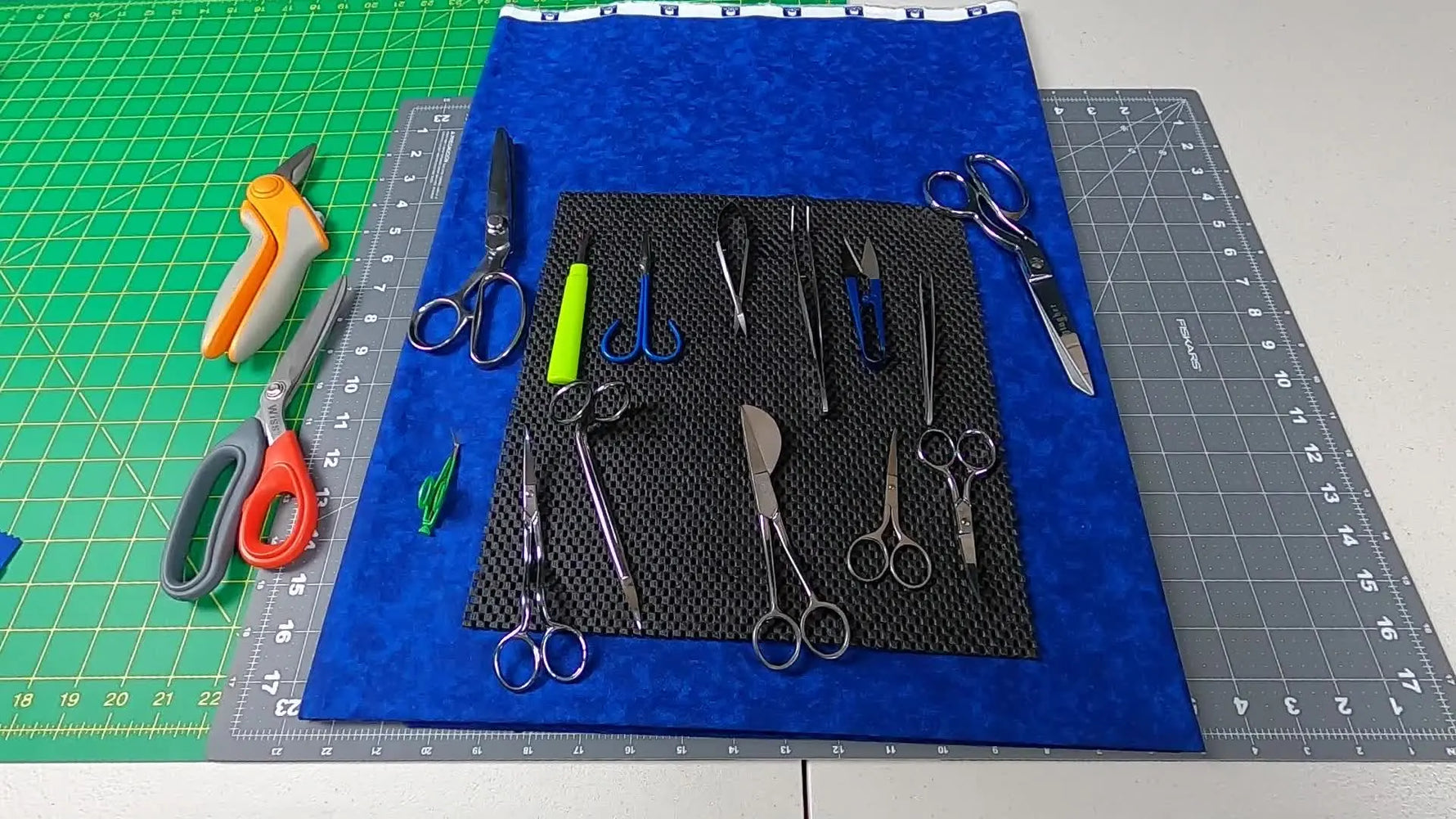 An overhead layout of a complete machine-embroidery cutting toolkit—snips, curved scissors, tweezers, and shears—ready for daily shop use.