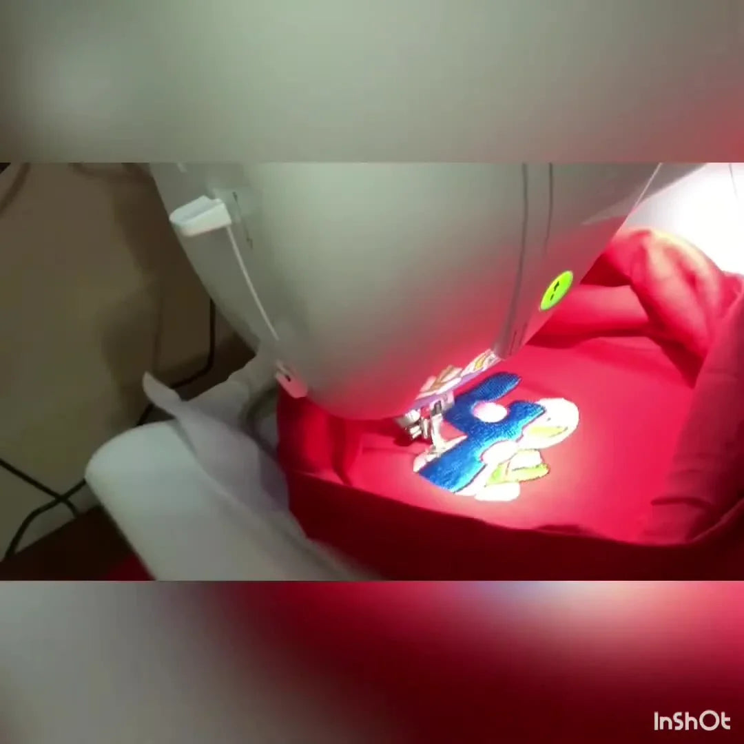 A close-up action shot of the Brother PE800 stitching a dinosaur design under the machine’s LED light.