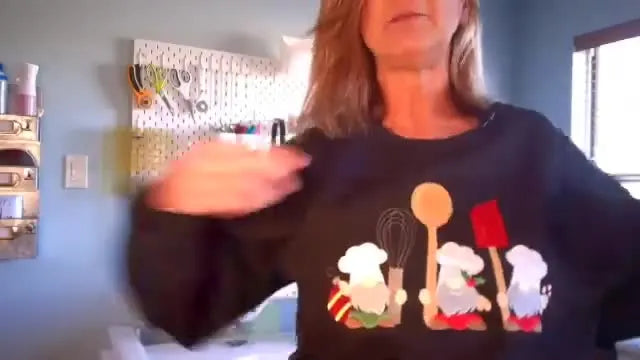 A finished black sweatshirt is shown being worn, featuring a large three-gnome embroidery design stitched cleanly across the chest.