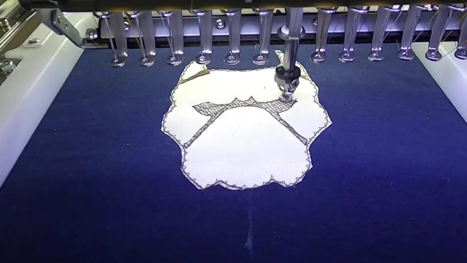 A multi-needle embroidery machine finishes a bold satin border on a dog appliqué while the hoodie is held firmly in a magnetic hoop.
